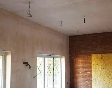 Freshly plastered interior room with smooth walls and ceiling, exposed wiring for lighting, and a mix of plaster and brick finishes, showcasing expert plastering service in the South West.