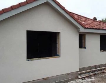 Exterior view of a newly built single-storey house with a smooth light render finish and red tiled roof, showing clean lines and precise workmanship typical of professional rendering services.